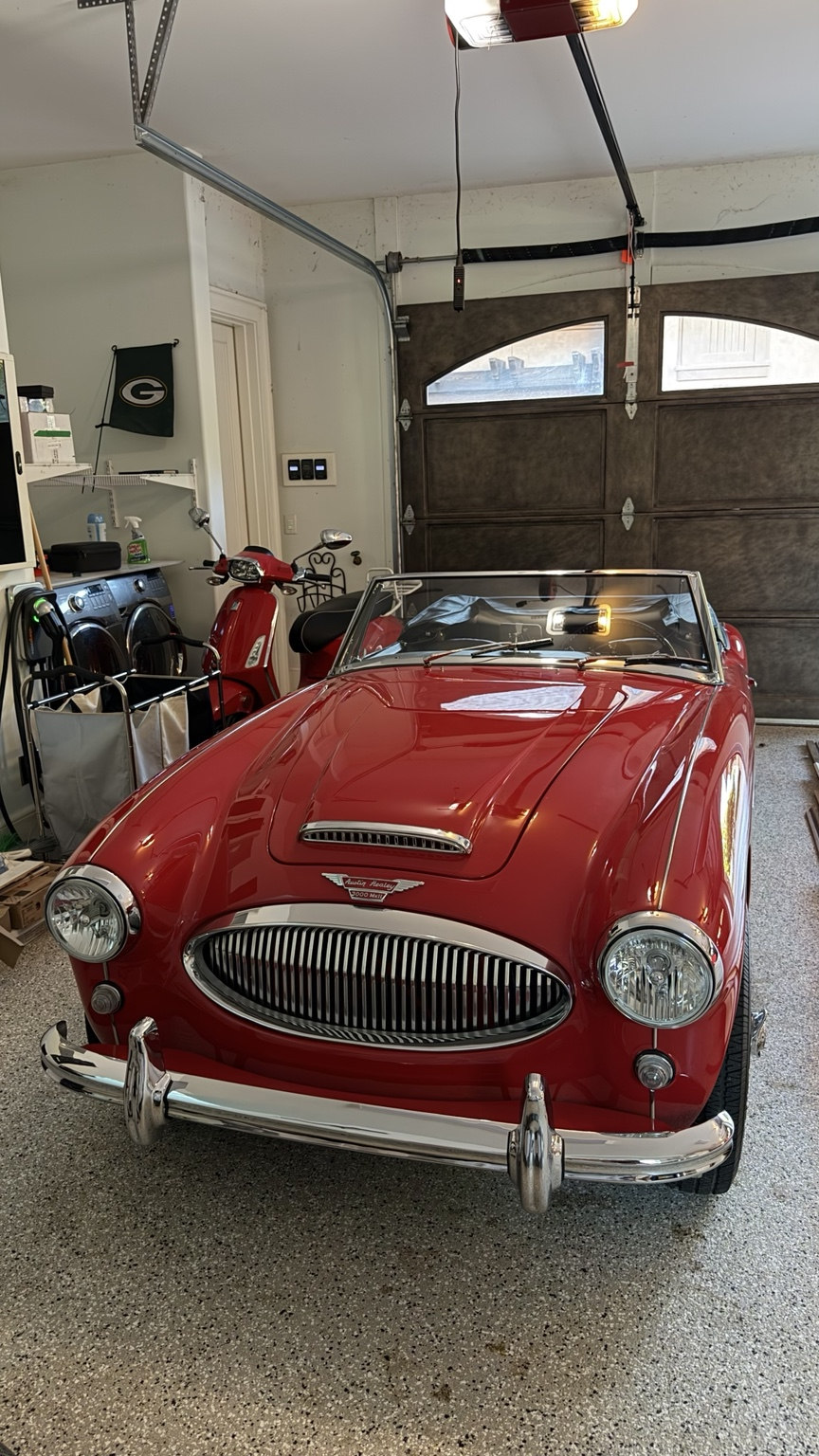 Red vintage Austin Healey convertible photographed in a garage