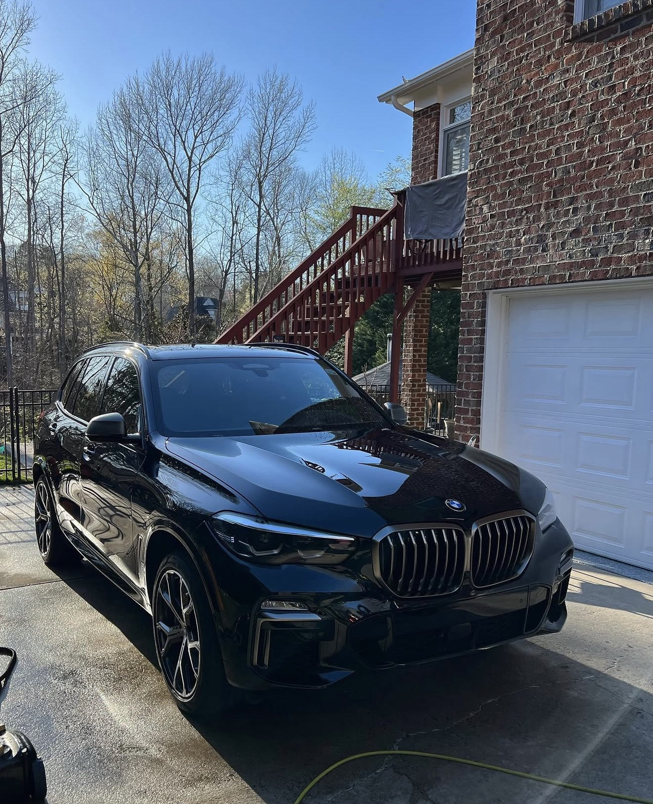 Glossy black BMW SUV photographed after detailing in a Charlotte-area driveway